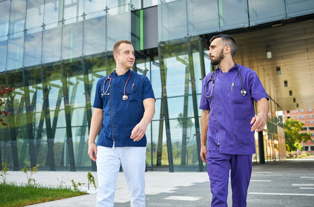 two male hospital professionals walking outside