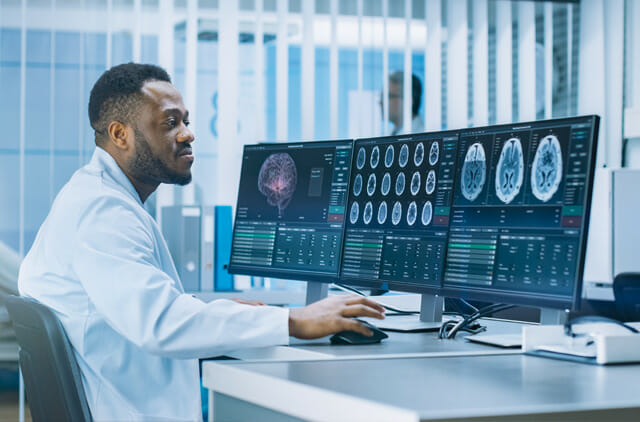 health care tech professional looking at image scans on computer screens