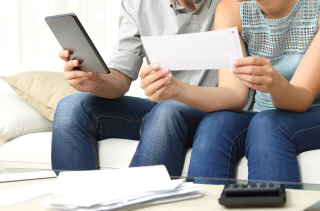 couple with bills and looking at their tablet